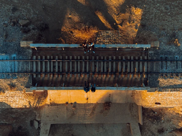 People sitting by railway tracks, birds eye view